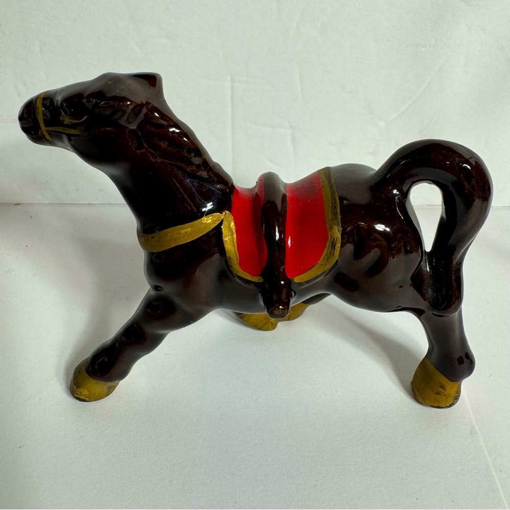 Vintage small brown ceramic horse figurine featuring gold trim and a red saddle.